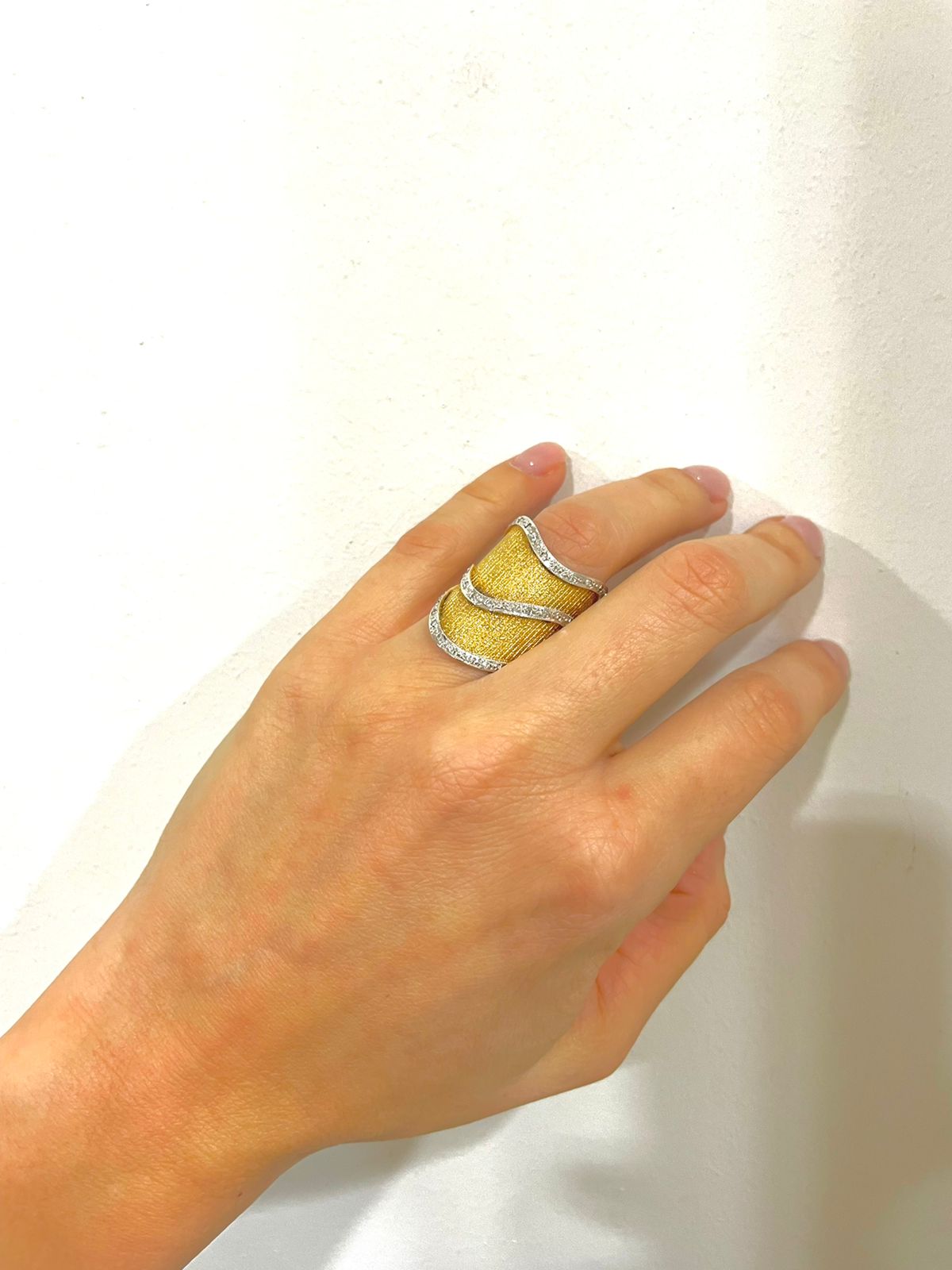 Εντυπωσιακό δαχτυλίδι σε συνδυασμό λευκού και κίτρινου χρυσού Κ18, με ριγέ ματ φινίρισμα και γυαλιστερές λεπτομέρειες
