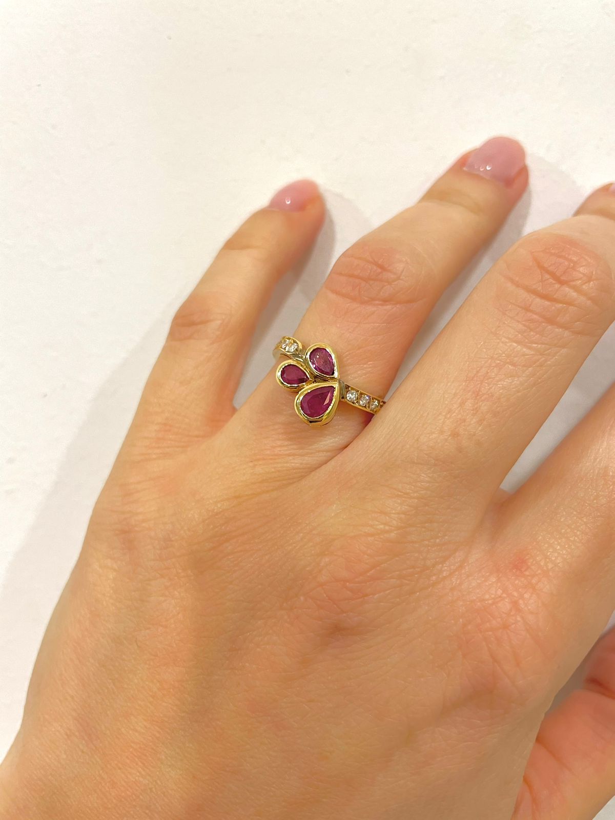 Μοντέρνο δαχτυλίδι από κίτρινο χρυσό Κ18 με τρία drop-shape σκούρα ροζ ζαφείρια και στρογγυλά διαμάντια μπριγιάν.