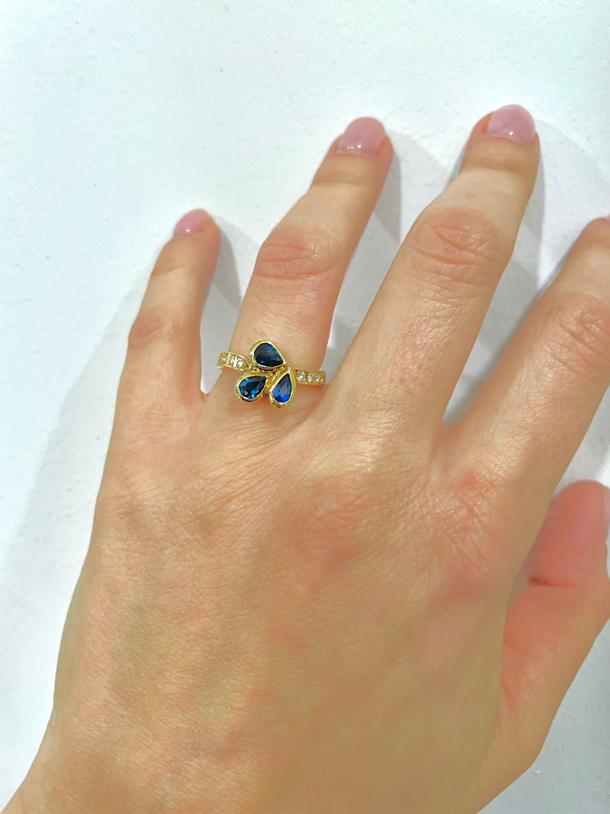 Μοντέρνο δαχτυλίδι από κίτρινο χρυσό Κ18 με τρία drop-shape σκούρα μπλε ζαφείρια και στρογγυλά διαμάντια μπριγιάν.